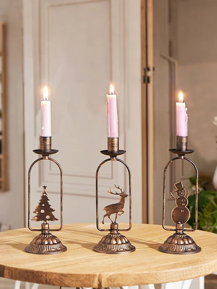 Three decorative candle holders with lit candles on a wooden surface.