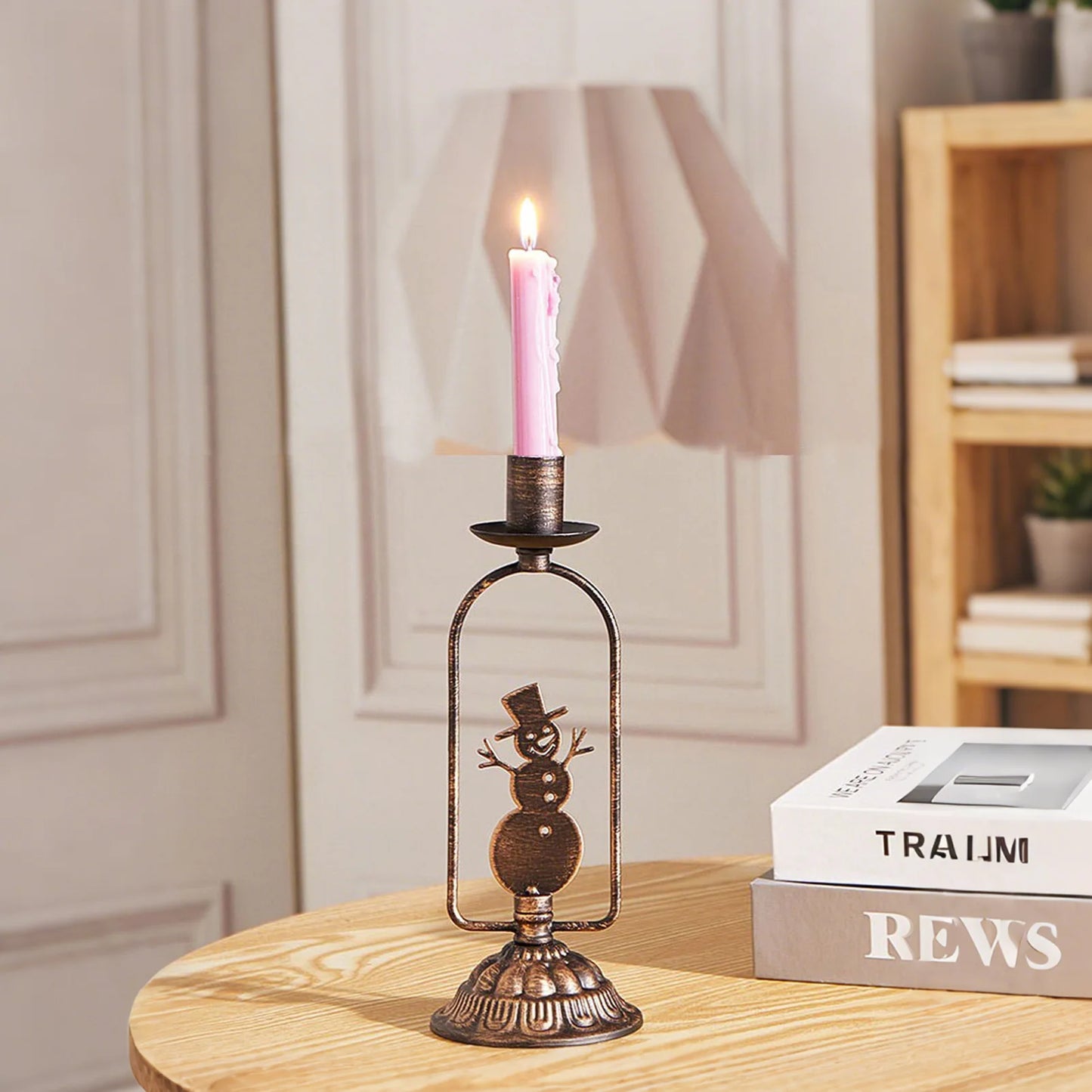 Decorative candle holder with a lit pink candle on a wooden table.