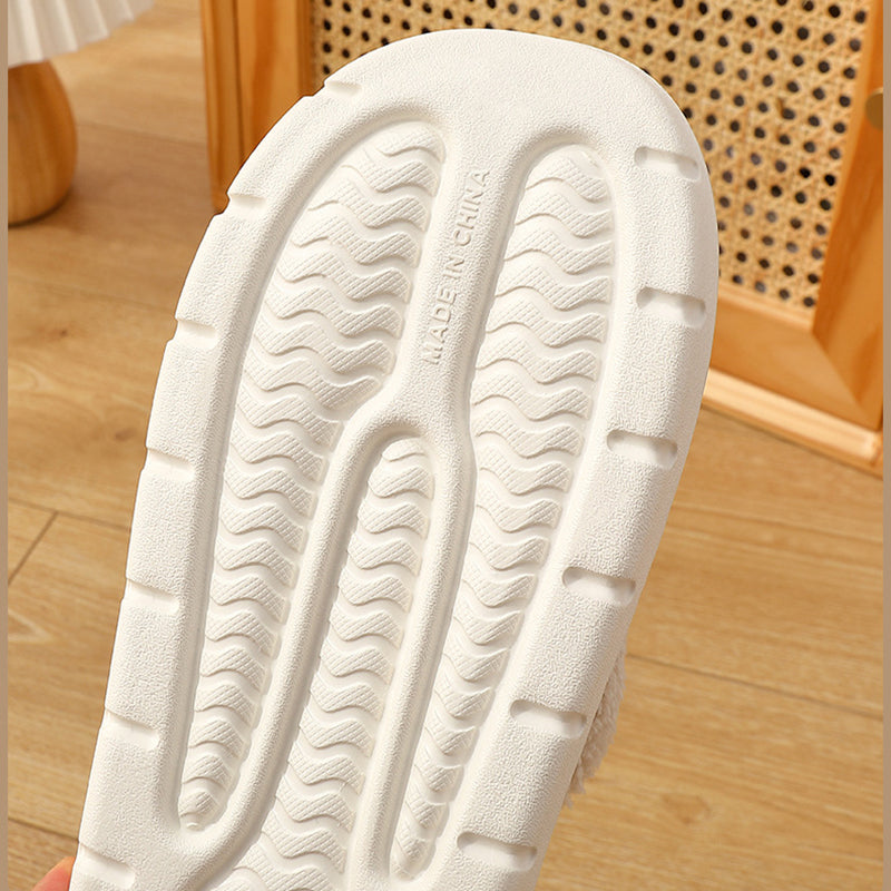 Close-up of a white shoe sole with tread pattern on a wooden floor.