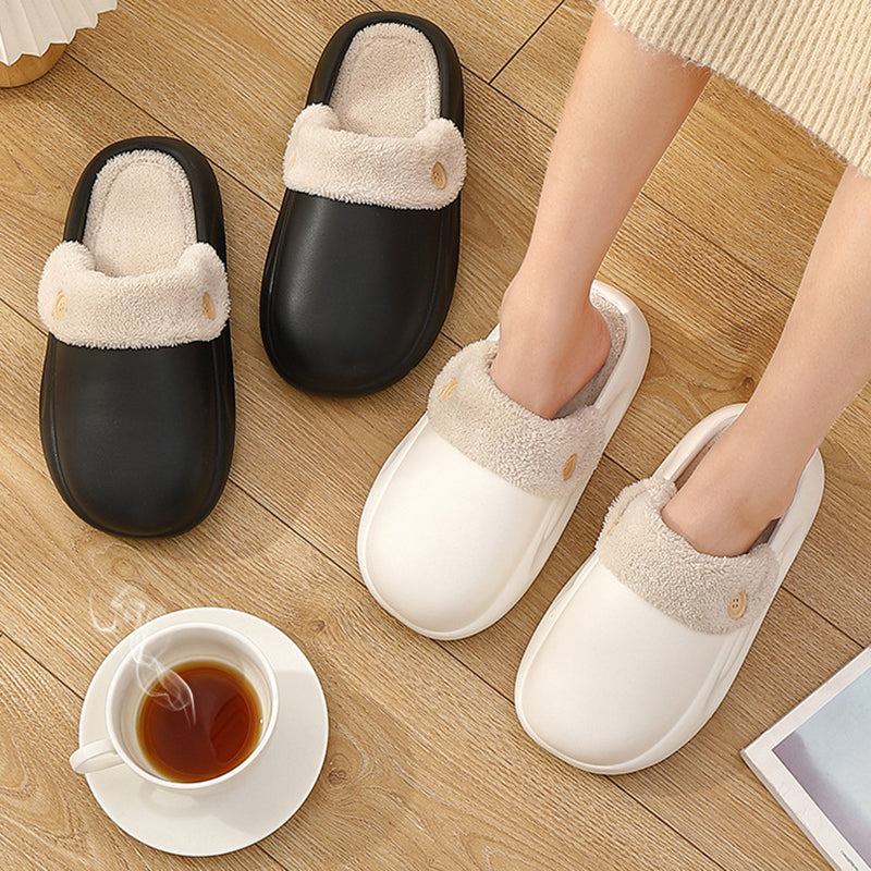 Black and white slippers on a wooden floor with a cup of tea and saucer.