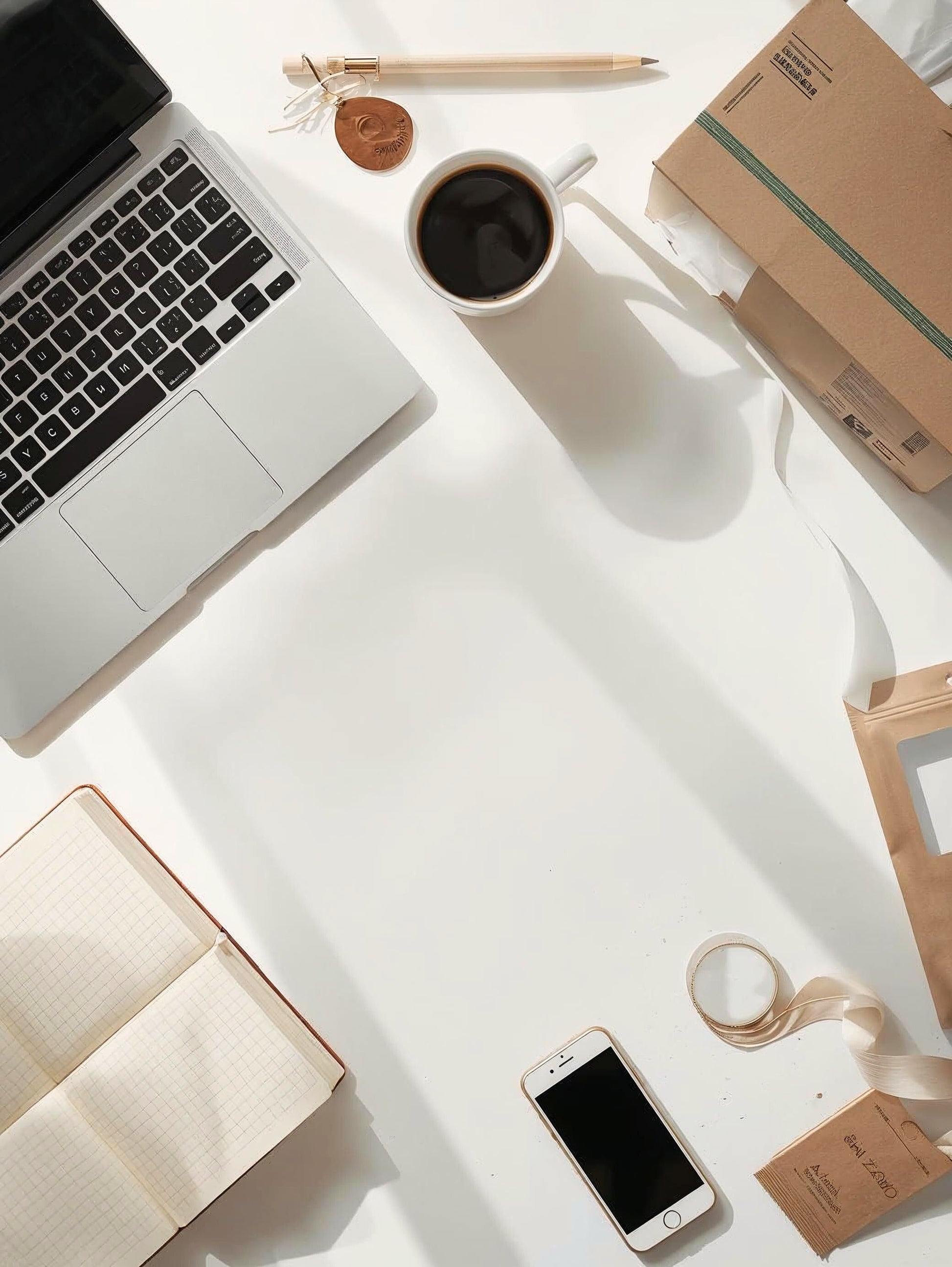 Neutral small business workspace with laptop coffee notebook and packaging supplies on clean desk with soft natural light