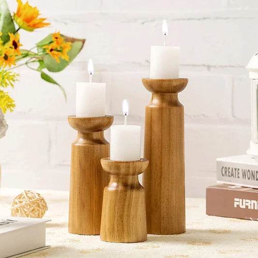 Three wooden candle holders with candles on a decorative surface.