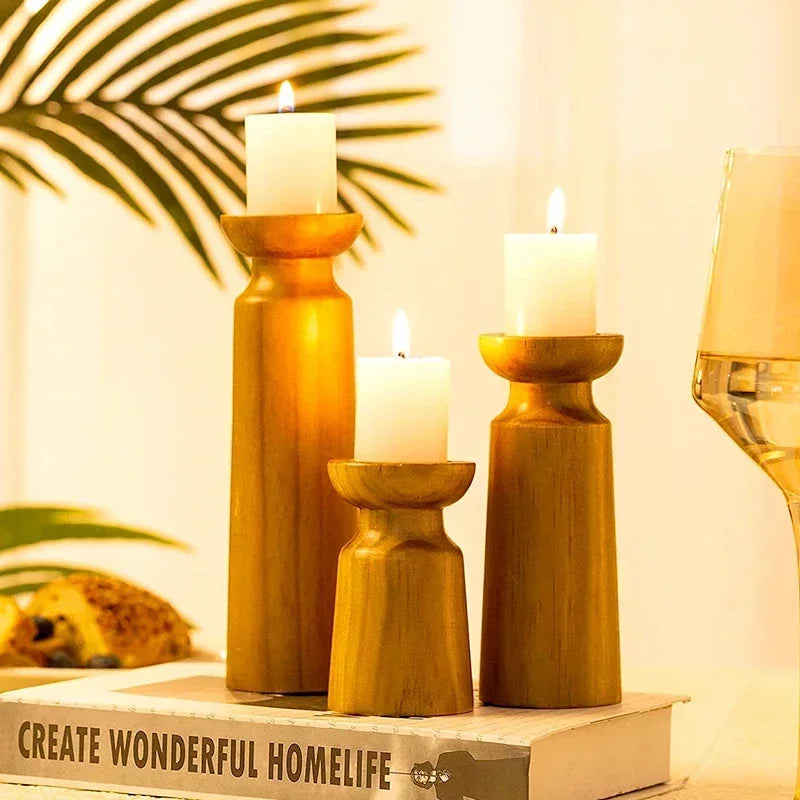 Three wooden candle holders with candles on a surface, with a book in the background.