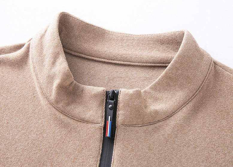 Close-up of a beige sweater with a zipper and brand logo on a white background