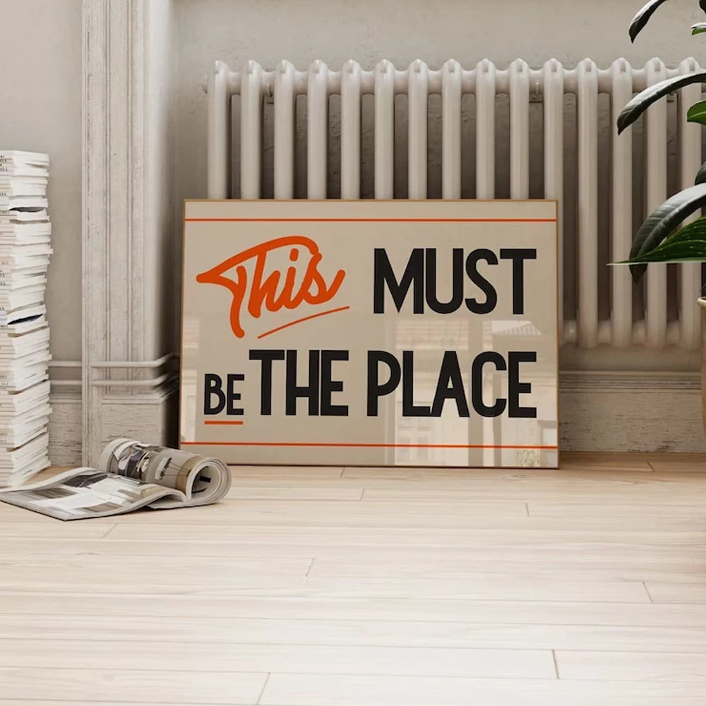 Retro typography poster reading “This Must Be The Place” in black and orange on canvas.