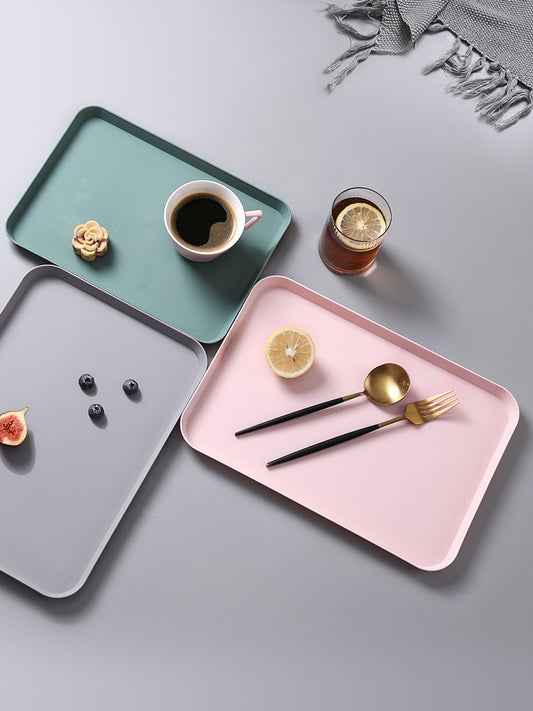 Three trays in green, pink, and gray with food and drink on a light gray background