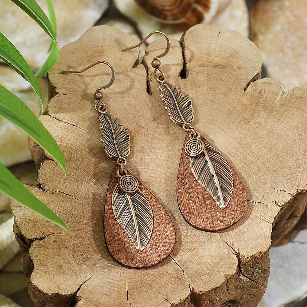 Wooden earrings with leaf designs on a wooden surface