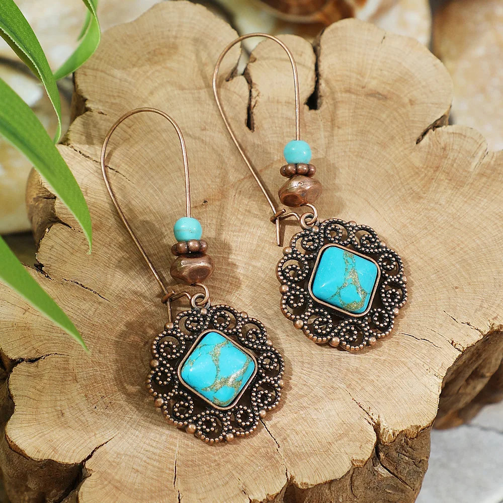 Pair of earrings with turquoise stones and brown beads on a wooden surface