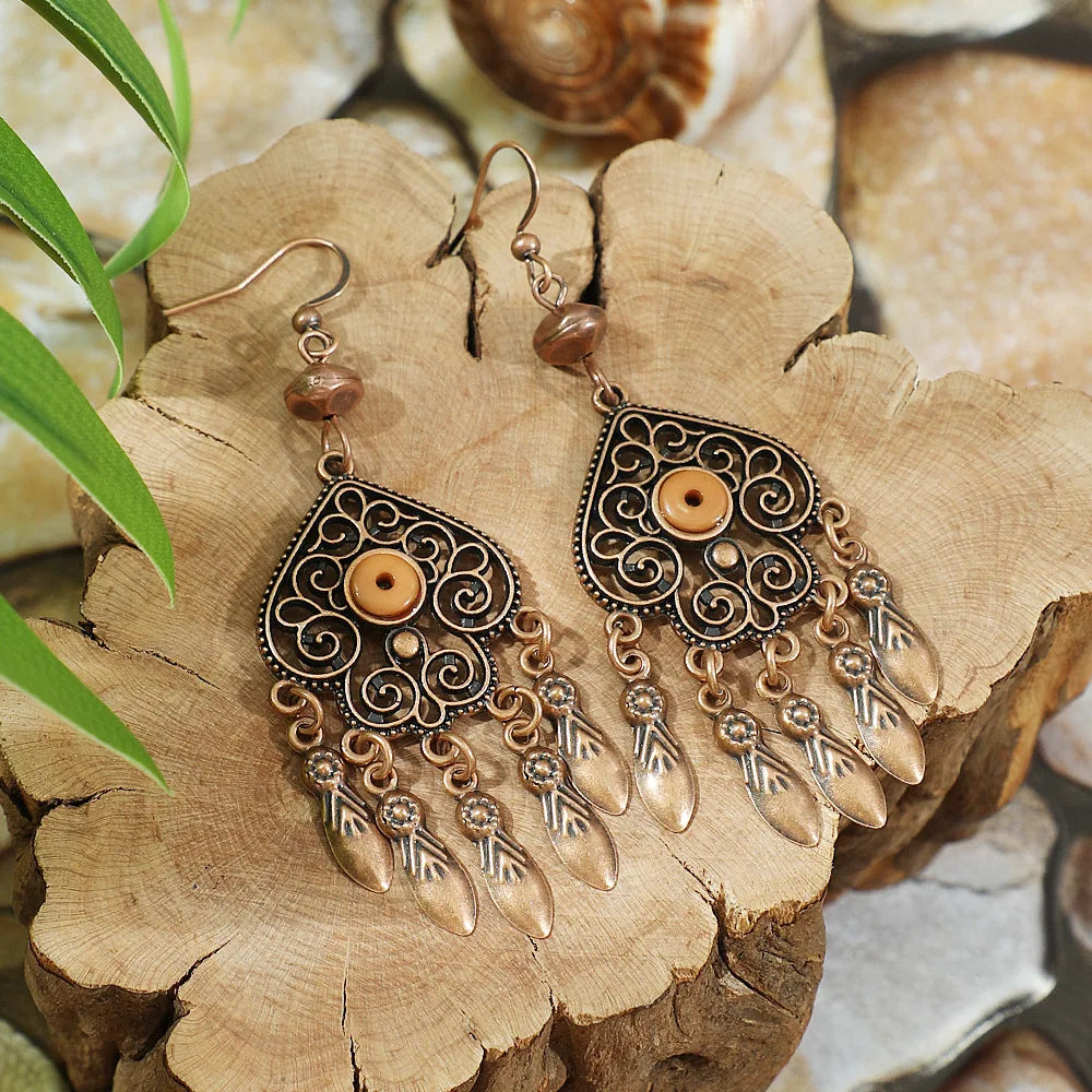 Ornate earrings with dangling elements on a wooden surface