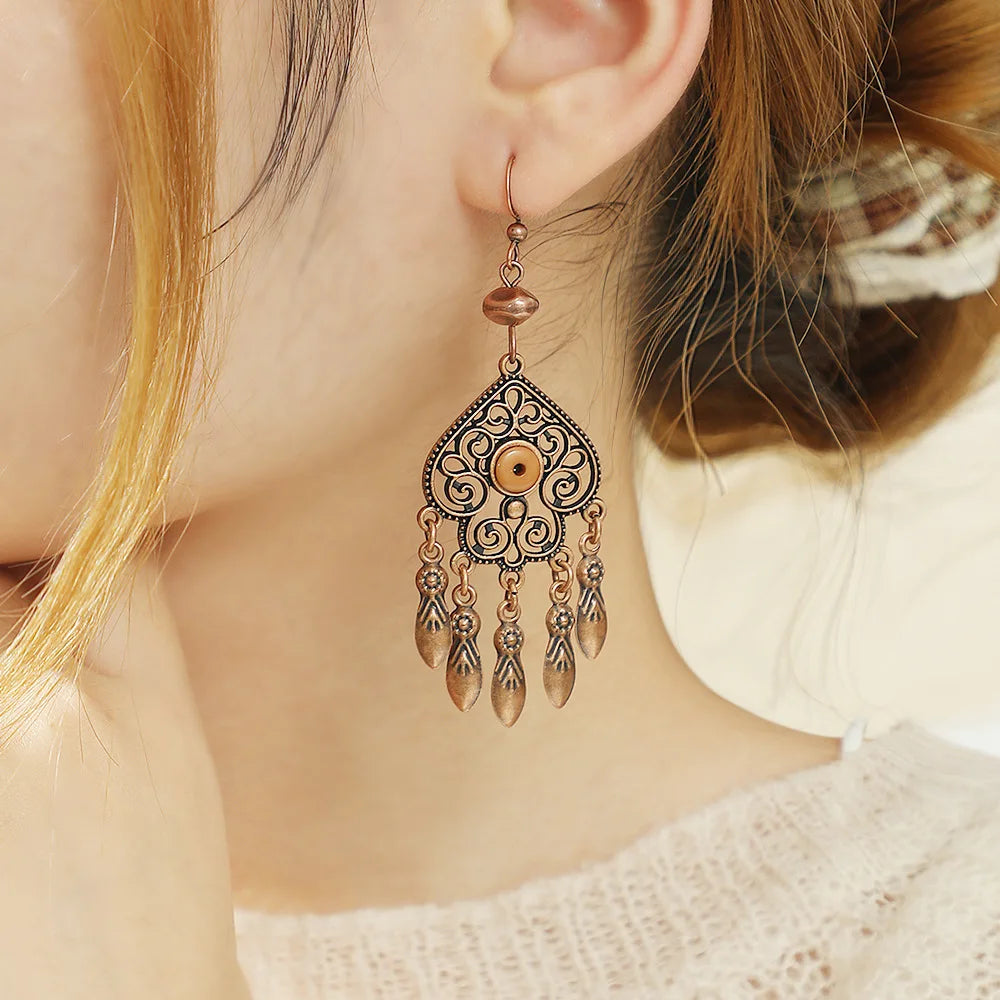 Close-up of a person wearing an ornate earring with dangling elements.