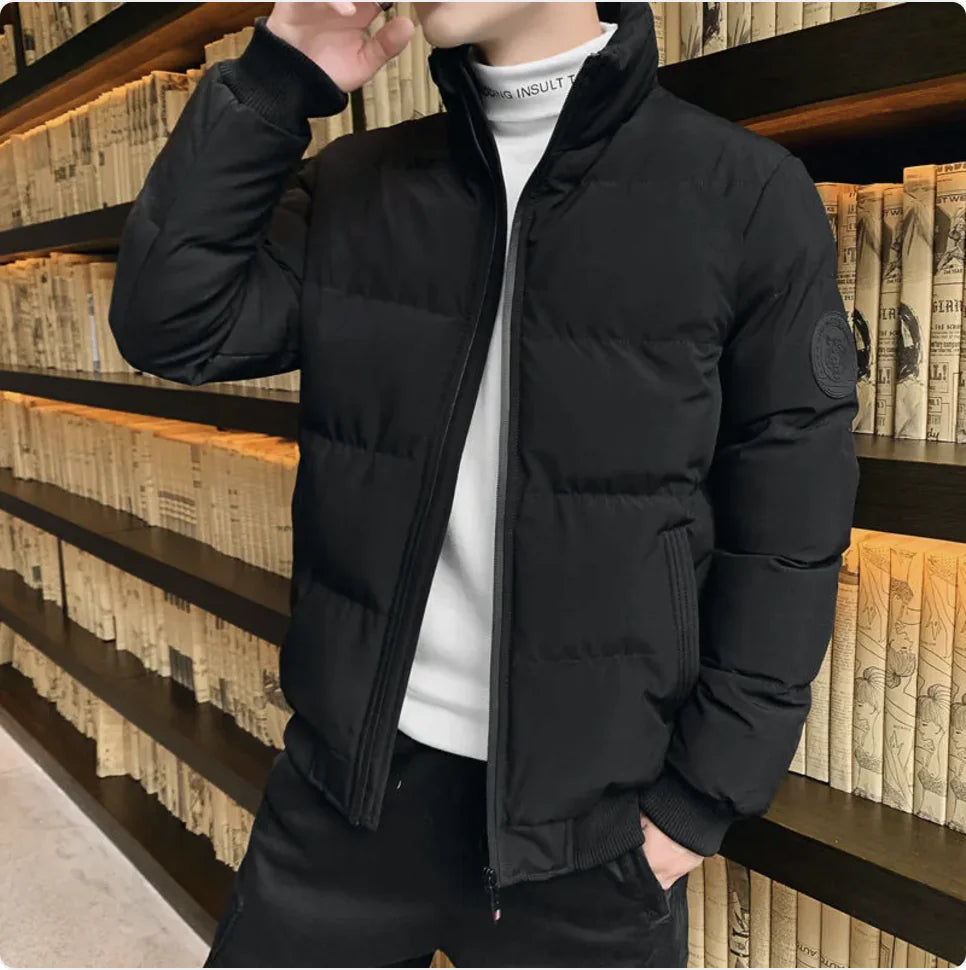 Person wearing a black puffer jacket in front of a bookshelf.