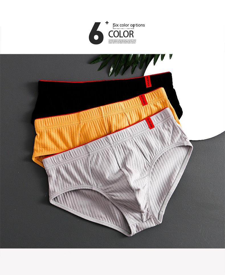 Three pairs of men's underwear in black, orange, and gray on a gray background.