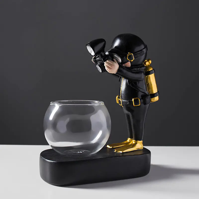 Figurine of a person in tactical gear with a camera next to a glass bowl on a dark background