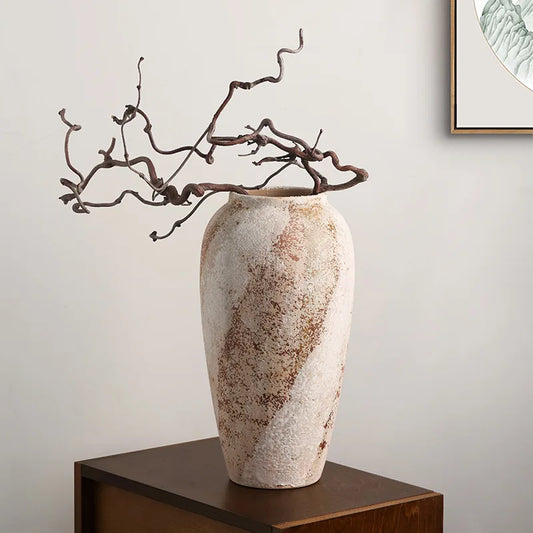 Decorative vase with textured surface on a wooden surface against a plain wall.