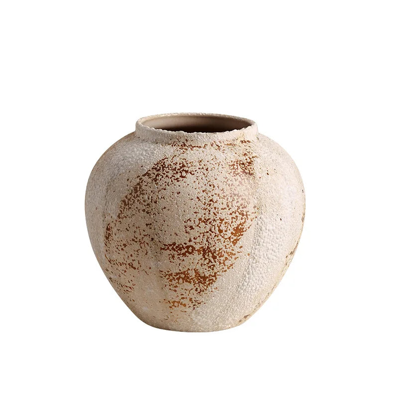 Round ceramic vase with textured surface and brown speckles on a white background