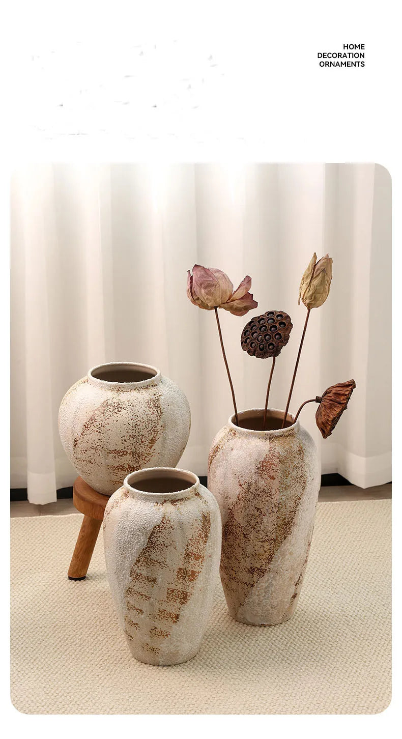 Three rustic ceramic vases with decorative elements on a light background