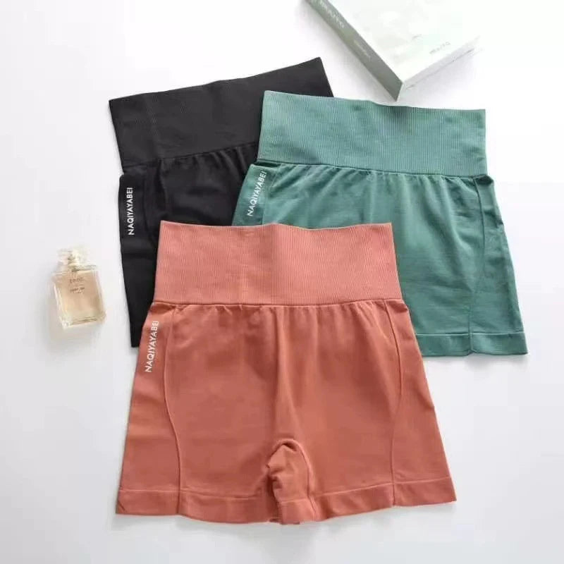Three pairs of shorts in black, green, and pink on a white background with a perfume bottle.