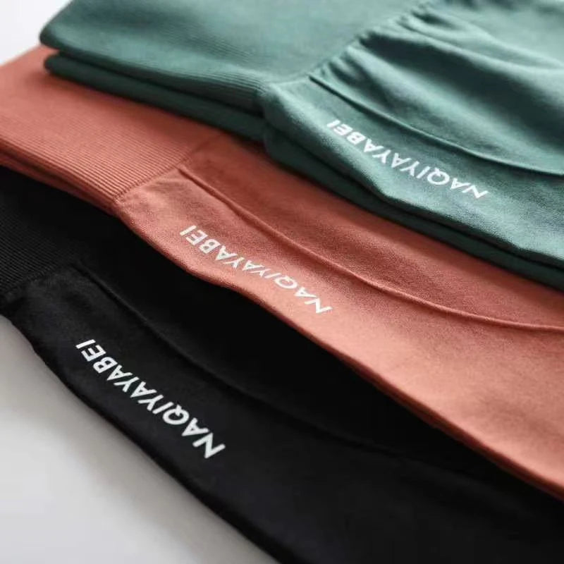 Stack of folded pants with 'NAGIYABEI' branding on a neutral background