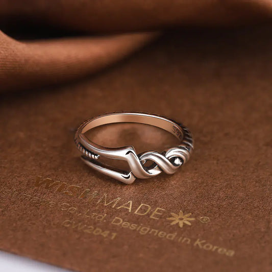 Silver ring with intricate design on a brown textured surface, featuring 'MADE' branding.