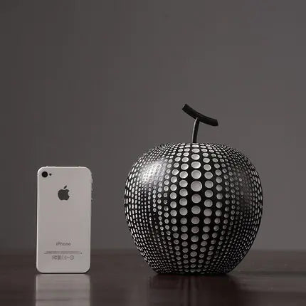Decorative apple sculpture next to a smartphone on a dark surface
