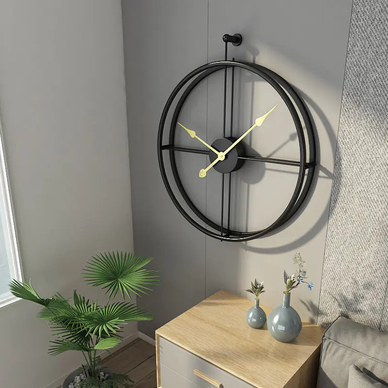 Decorative wall clock with black metal frame and yellow hands on a light gray wall.