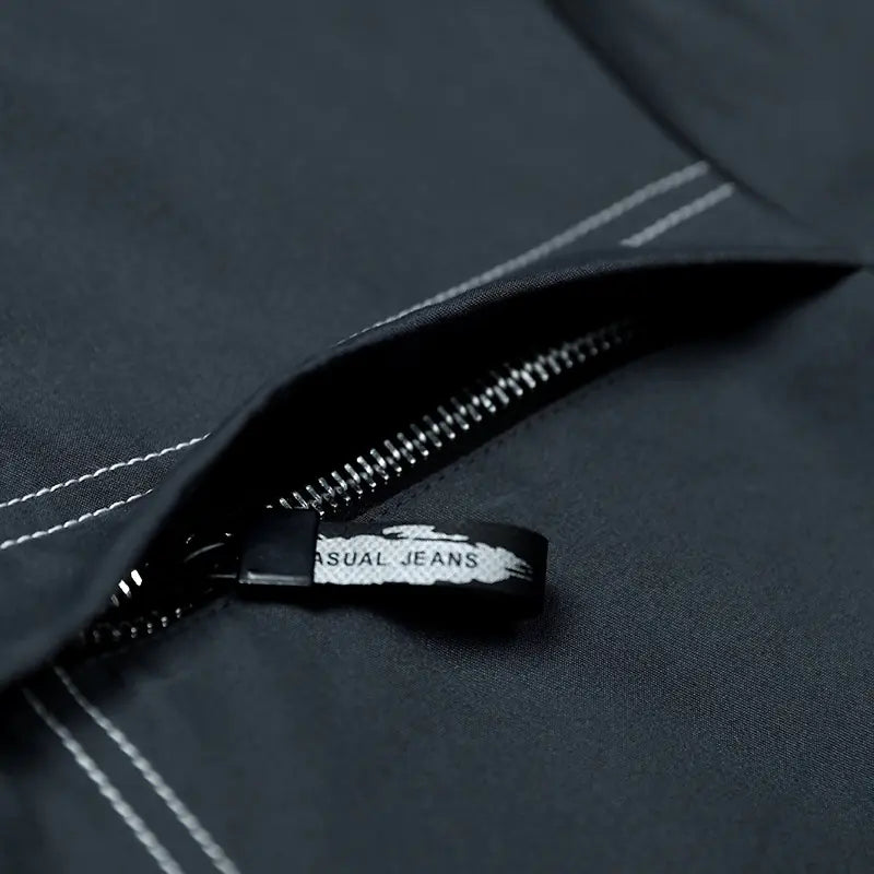 Close-up of a zipper on a dark fabric with 'SUAL JEANS' branding.