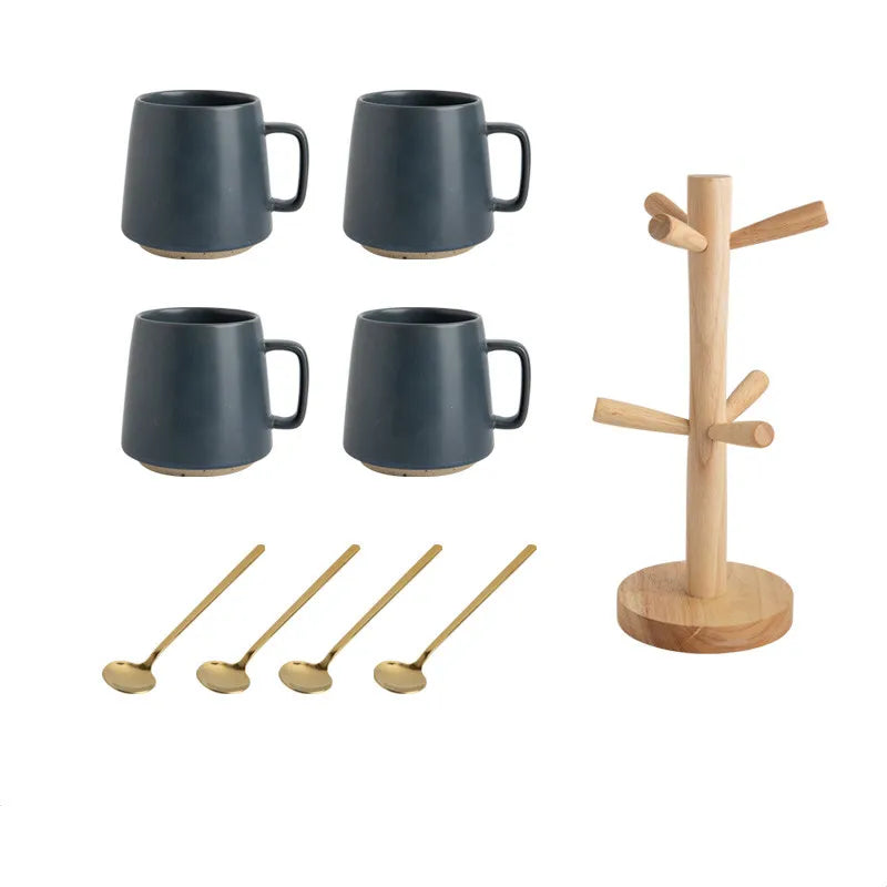 Set of four dark blue mugs, four wooden spoons, and a wooden mug tree on a white background