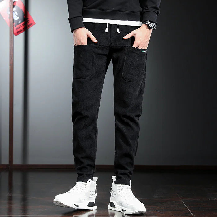 Person wearing black cargo pants with white sneakers on a dark background